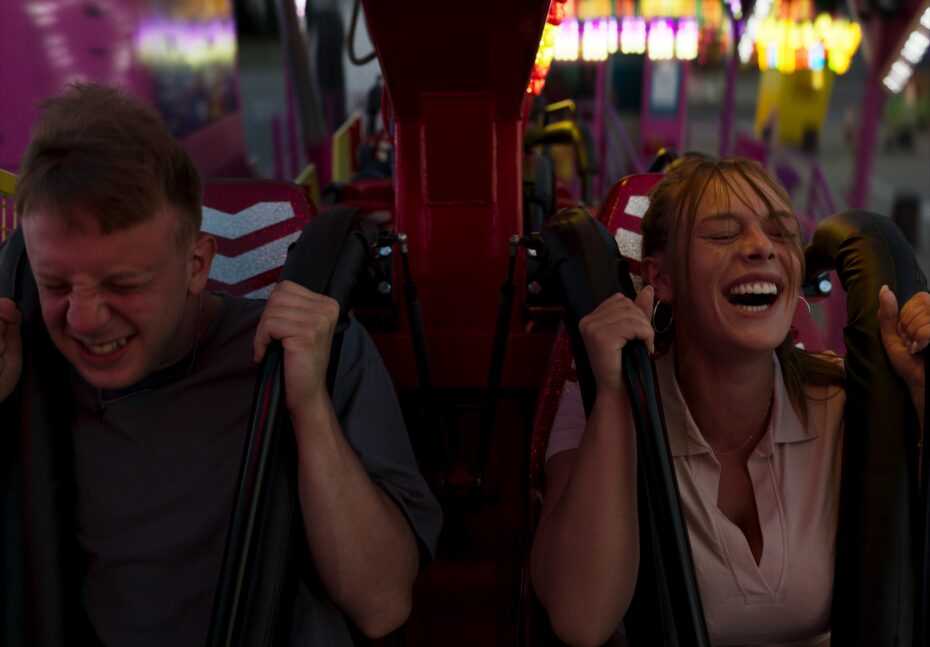 Na zdjęciu młody chłopak i młoda dziewczyna na rollercoasterze.
