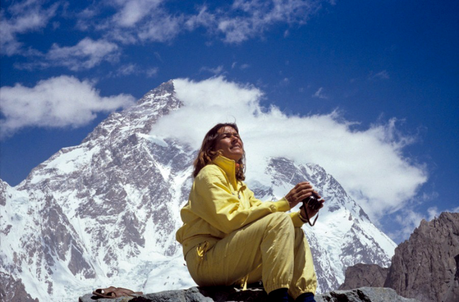 Na zdjęciu kobieta siedząca na tle szczytu górskiego.