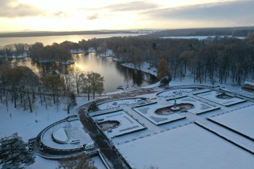 Pokryty śniegiem park widoczny z góry i niebo z zachodzącym słońcem.