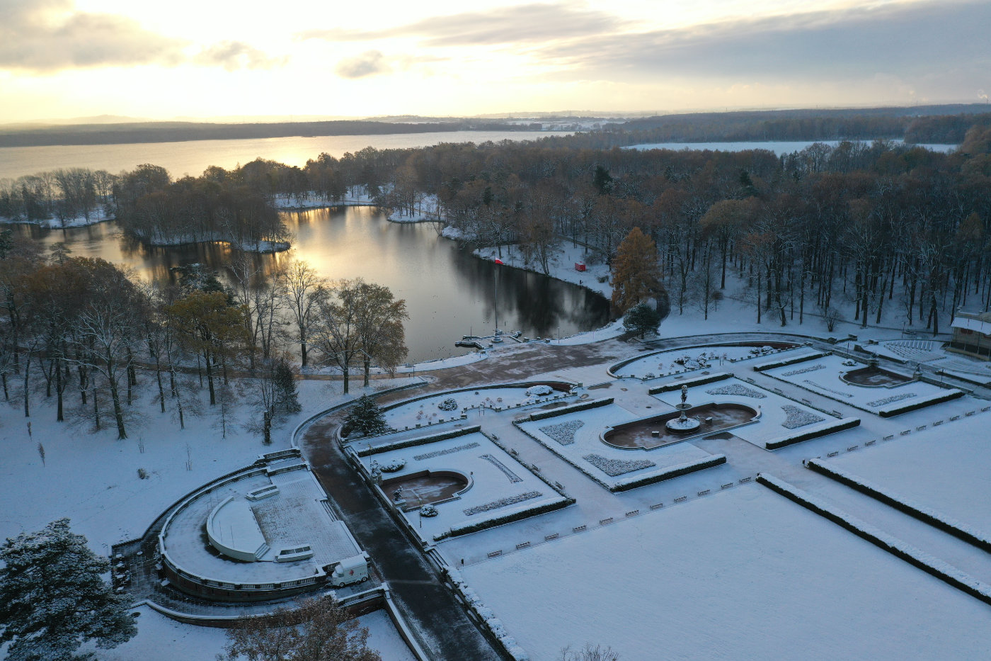 Pokryty śniegiem park widoczny z góry i niebo z zachodzącym słońcem.