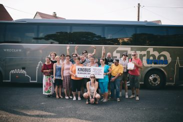 Grupa osób stających przed autokarem
